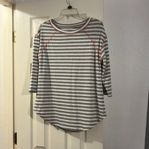 Maurice’s small shirt with gray and white stripes has pink on the top.